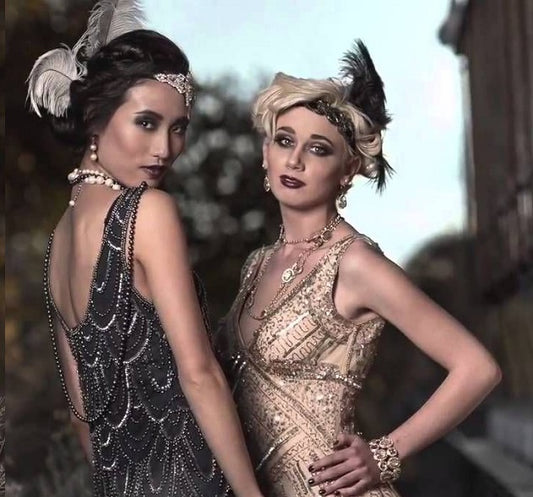2 ladies wearing 1920s style flapper dresses