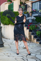 A black 1920s flapper dress with sleeves, black sequins, beads and fringes