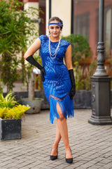 A 1920s Flapper Dress in Electric Blue. It has beads, sequins and finished with a layer of fringes around the hem.