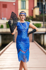 A 1920s Flapper Dress in Electric Blue. It has beads, sequins and finished with a layer of fringes around the hem.