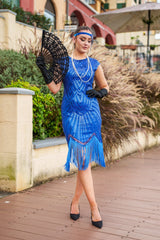 A 1920s Flapper Dress in Electric Blue. It has beads, sequins and finished with a layer of fringes around the hem.