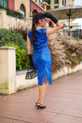 A 1920s Flapper Dress in Electric Blue. It has beads, sequins and finished with a layer of fringes around the hem.