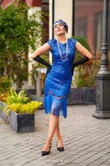A 1920s Flapper Dress in Electric Blue. It has beads, sequins and finished with a layer of fringes around the hem.