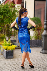 A 1920s Flapper Dress in Electric Blue. It has beads, sequins and finished with a layer of fringes around the hem.