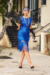 A 1920s Flapper Dress in Electric Blue. It has beads, sequins and finished with a layer of fringes around the hem.