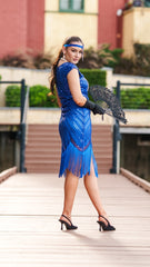 A 1920s Flapper Dress in Electric Blue. It has beads, sequins and finished with a layer of fringes around the hem.