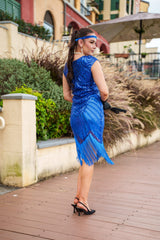 A 1920s Flapper Dress in Electric Blue. It has beads, sequins and finished with a layer of fringes around the hem.