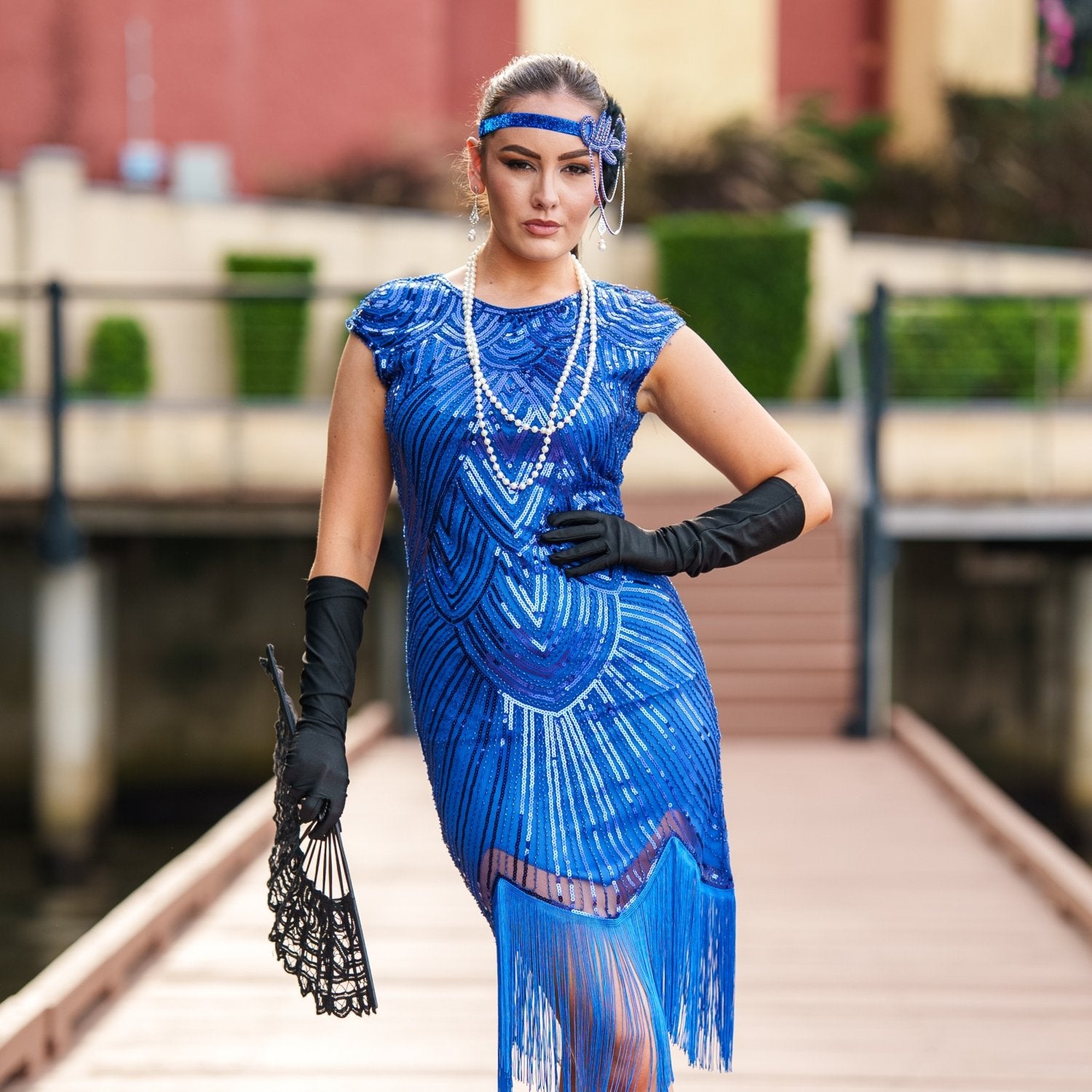 A 1920s Flapper Dress in Electric Blue. It has beads, sequins and finished with a layer of fringes around the hem.