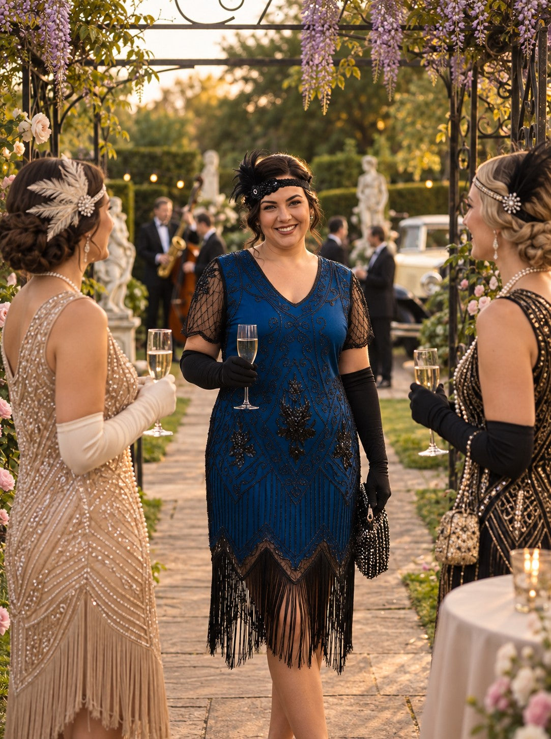 A woman in a 1920s-style blue beaded flapper dress stands in an outdoor garden walkway, smiling and holding a champagne flute, flanked by two other women in elegant flapper dresses.