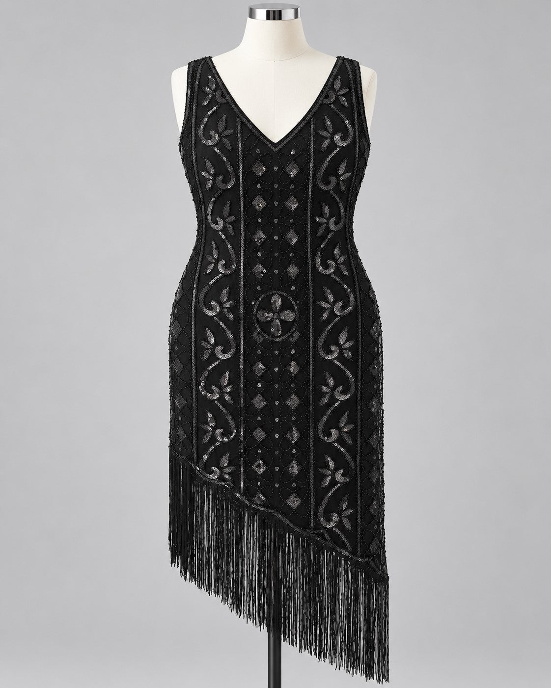 A black sleeveless flapper-style dress with silver beaded vertical panels, floral motifs, and long fringe along the asymmetrical hem, displayed on a mannequin against a light gray background.