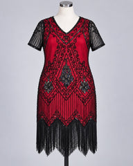 A red and black 1920s-style flapper dress displayed on a mannequin against a light gray studio background. The dress features black sequin fringe, black embroidered scrollwork, and sheer black short sleeves.