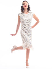 A vintage 1920s flapper dress in ivory white with beads, sequins and fringes around hem.