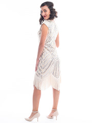 A back view of a vintage 1920s flapper dress in ivory white with beads, sequins and fringes around hem.